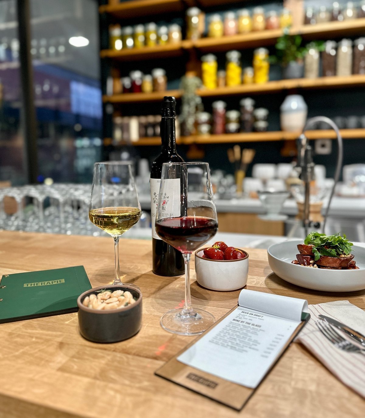 Wine glasses, small plates, and the pantry shelves along the Therapie bar