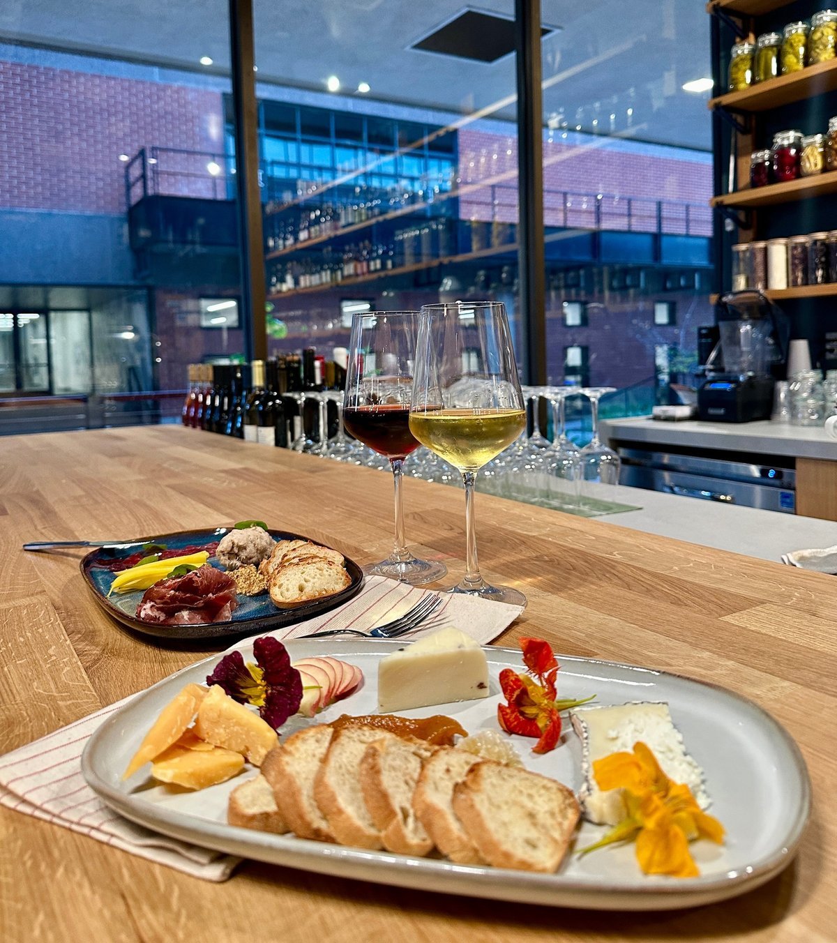 Cheese and charcuterie plates with two glasses of wine on the bar counter, courtyard beyond
